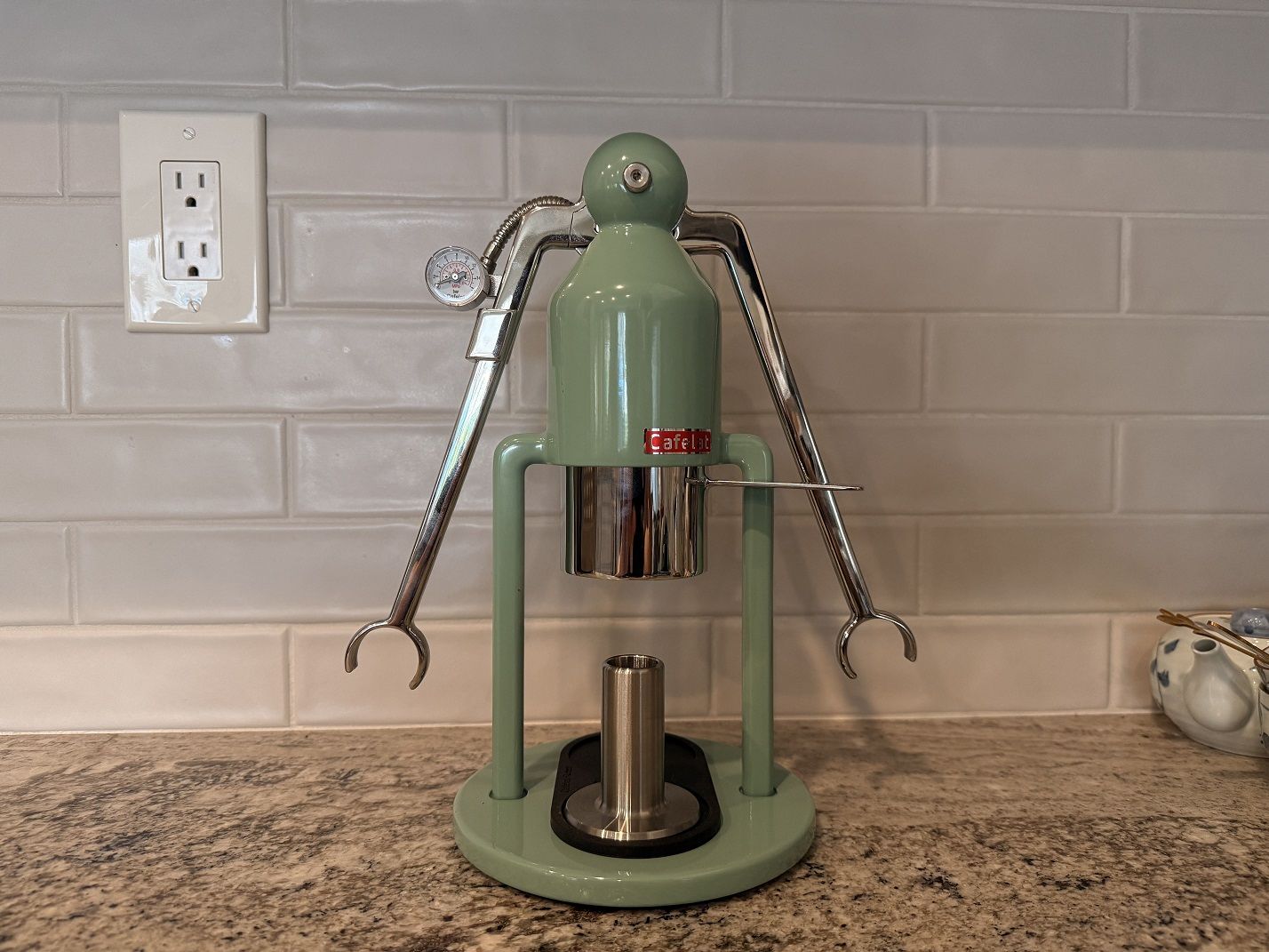 The Cafelat Robot Barista lever espresso maker in retro green against a tiled kitchen backsplash.