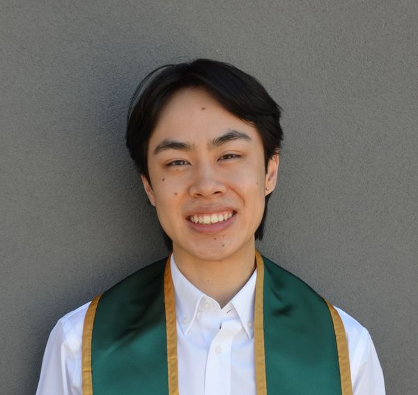 Professional shoulders-up photo of the author wearing a green and gold stole over a white collared shirt